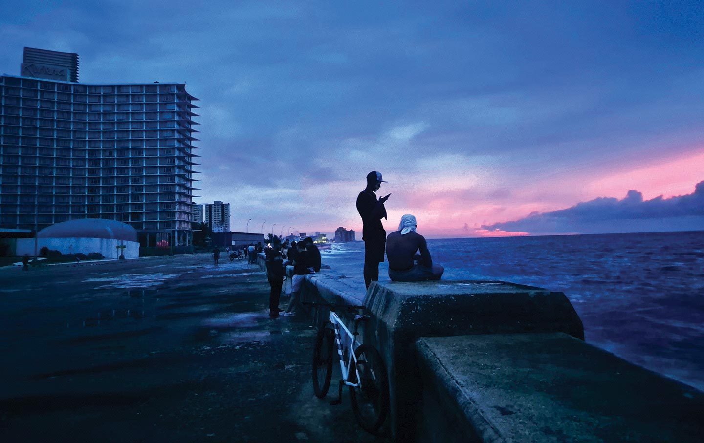 People gather against a backdrop of unlit buildings in Havana, as Cuba’s national power grid has effectively collapsed.