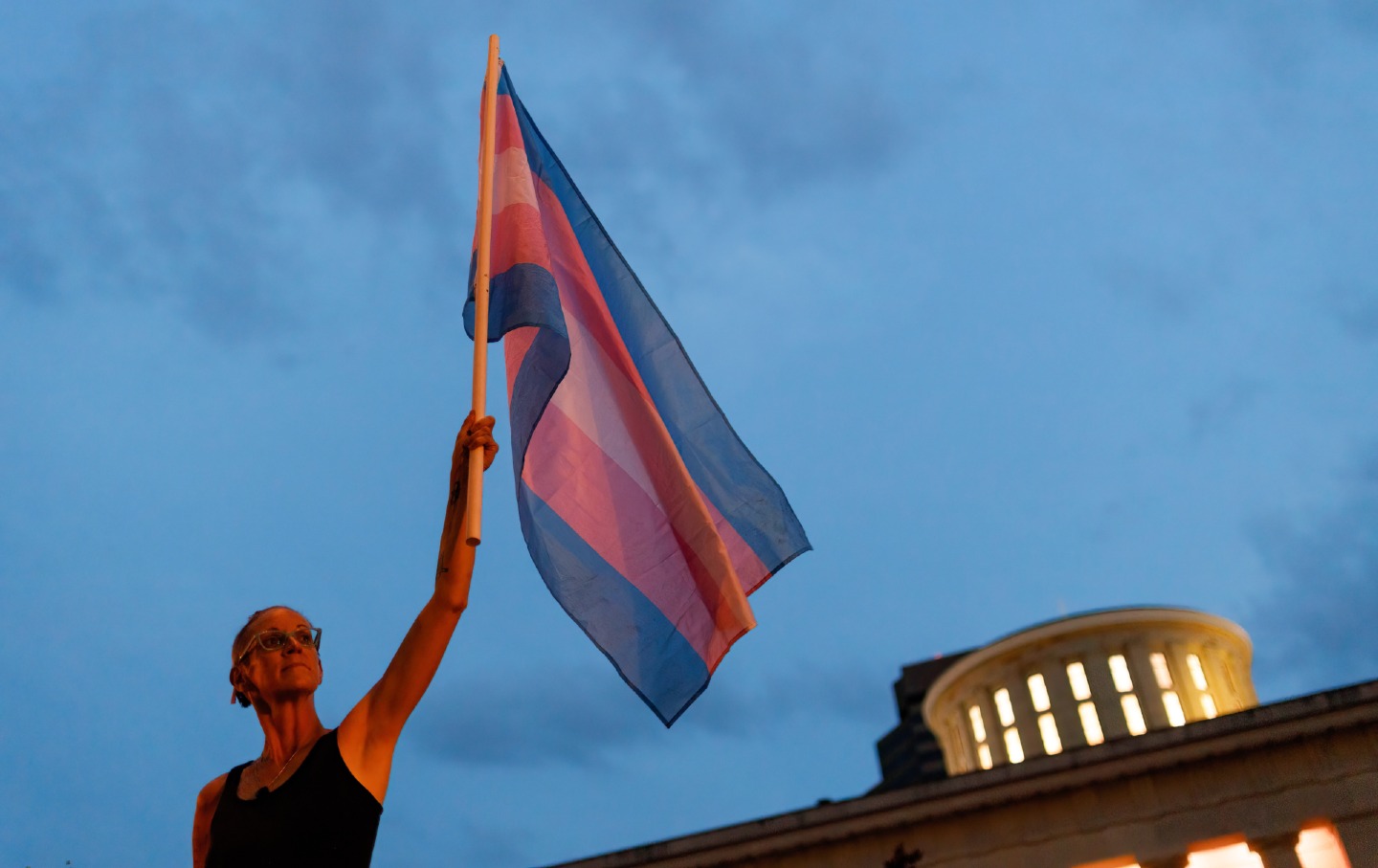 Cole Ramsey holds a transgender pride flag in front of the Ohio Statehouse on June 24, 2021, to protest the passing of legislation against trans women playing sports in high school and college.